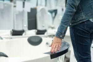 woman gliding hand over hot tub in a store, as if to determine if its the one for her.